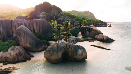 Stunning tropical beach on Coco island at Seychelles, giant granite rocks on the beaches, happy Young couple man and woman walking n the beach