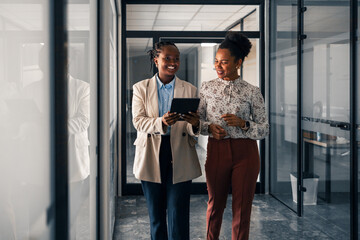 Two Professional Women Discussing Work While Walking in a Modern Office