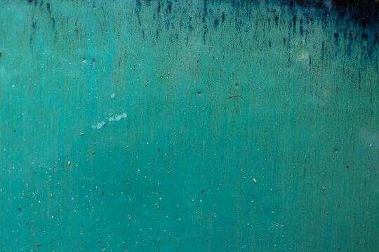 Abstract glaze texture in a bright turquoise hue, with dark color streaks flowing down from the top. Abstract background, ocean, or ceramic material