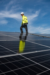 Technician installing solar panels on factory roof for green energy. A skilled technician in safety gear is working on a solar panel installation on rooftop.