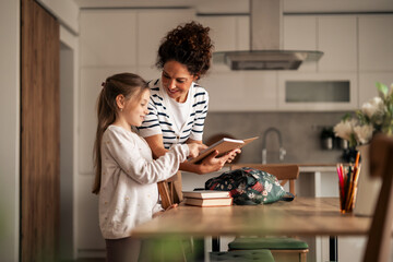 Mother Helping Daughter Prepare For School in a Modern Kitchen Setting