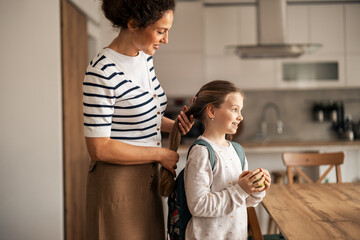 Mother Prepares Daughter for School in a Warm Domestic Kitchen Setting