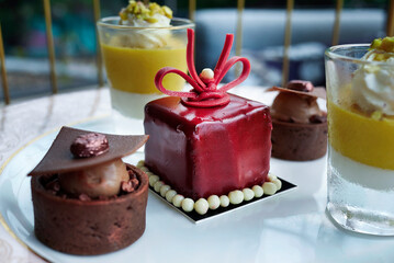 Luxury afternoon tea petit set dessert platter featuring red mirror glaze mousse cake and chocolate tartlets.