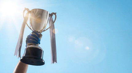 A trophy is held up high by a winner in a local park. This moment marks the achievement of success in a sports competition during summer. Friends and family gather around to celebrate.