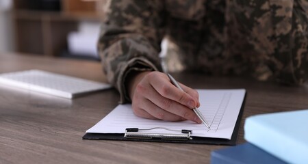 Military education. Student in soldier uniform learning at wooden desk indoors, closeup. Space for...