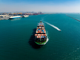 Aerial view of container vessel sailing near port breakwater for infrastructure business