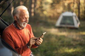 Senior Man Using Smartphone During a Peaceful Forest Camping Adventure