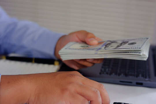 A man gives a wad of banknotes to his client at the office. The concept of corruption and bribery.