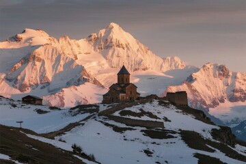 Snow-capped mountains at sunset with a historic church on a ridge