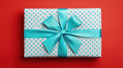 Elegant gift box with turquoise ribbon and polka dot wrap on vibrant red background