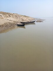 Wooden boats moored on a muddy riverbank under a clear sky