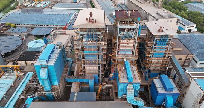 Aerial shot of complex industrial factory machinery and equipment with solar panels on roof.