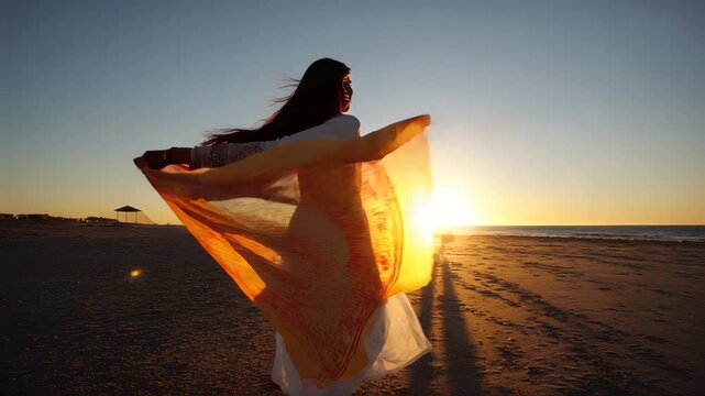 woman wearige white kurta standing on the beach at sunset, with her hair blowing in the wind and holding up a flowing dupatta that is draped over one shoulder