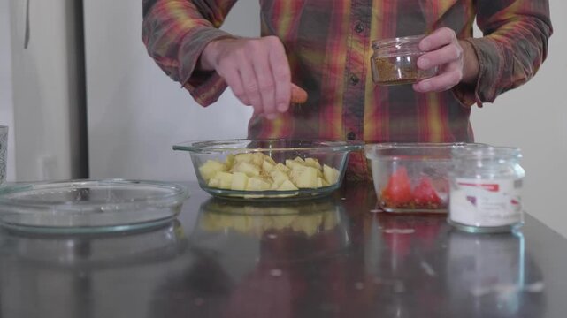 Preparing Roasted Potatoes: Chef Adding Spices from a Jar to Cubed Potatoes.