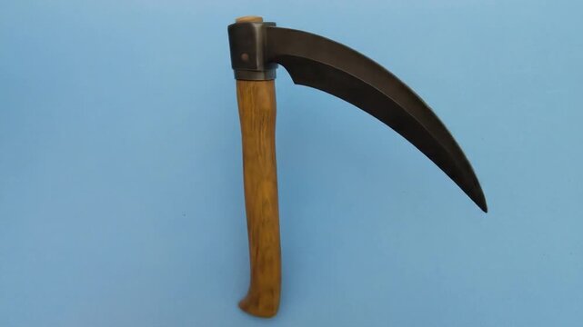 A curved metal blade affixed to a wooden handle, lying on a blue backdrop