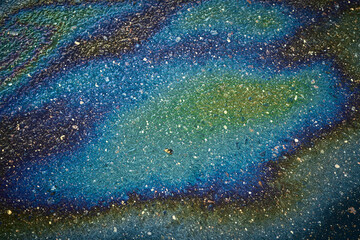 Fototapeta premium Oil Sheen on Pavement Shows Rainbow Colors Near Busy Street During Afternoon