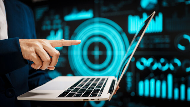 Professional working on laptop in front of futuristic digital dashboards, highlighting data analytics, cybersecurity insights, real-time visual information that reflect modern technology. - Powered by Adobe