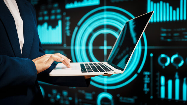 Professional working on laptop in front of futuristic digital dashboards, highlighting data analytics, cybersecurity insights, real-time visual information that reflect modern technology. - Powered by Adobe