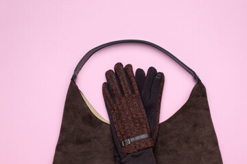 Fashionable Winter Accessories: Brown Suede Bag and Stylish Gloves on Pink Background