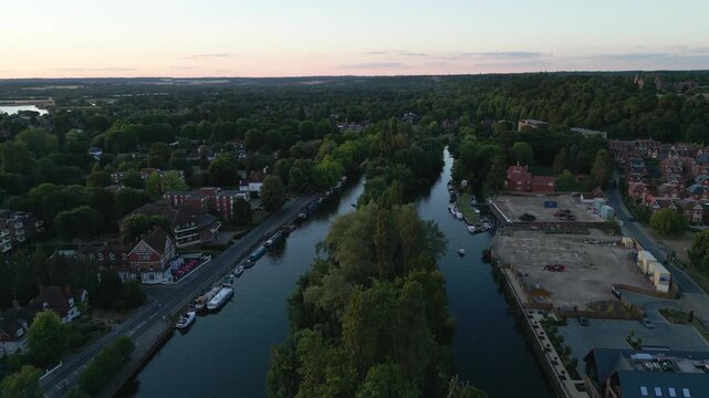Aerial view of a riverbend lined with trees and buildings at dusk.