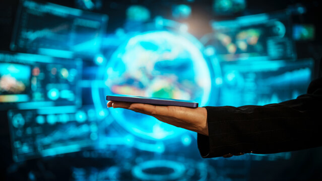 Business woman holding smartphone in front of futuristic digital interface, global communication, technology networking, data connectivity, mobile interaction, high-tech environment. - Powered by Adobe