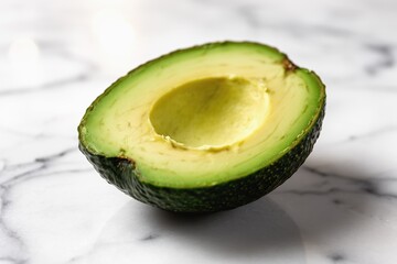 Fresh avocado half with vivid green flesh on white marble surface, studio-lit