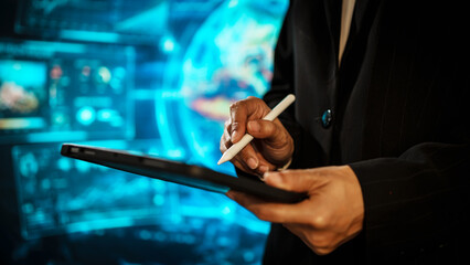 Business woman using tablet in front of a futuristic digital interface, representing data analysis, global technology, virtual communication, innovation, modern workflow in high-tech environment.