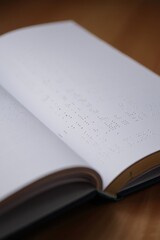 Open Braille book with embossed dot text, curled pages and hardcover binding