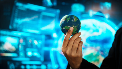 Business professional holding small Earth model before futuristic digital interface, global responsibility,environmental awareness,world protection, sustainability, modern international collaboration