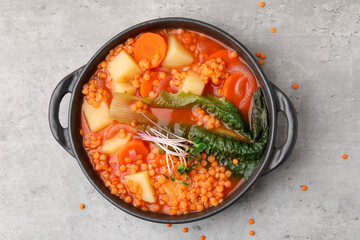 Tasty lentil soup in bowl on grey table, top view