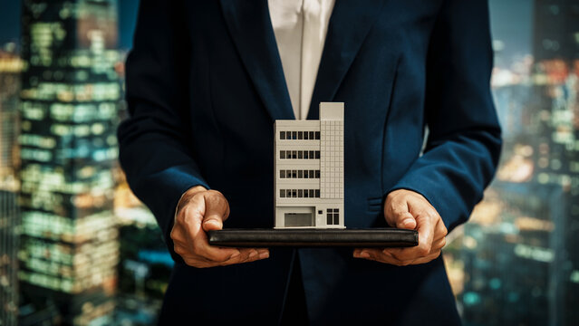 Businesswoman presents modern building model against a vibrant cityscape, real estate investment, property development, strategic planning, corporate decision-making in the commercial property sector