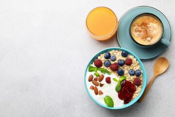 Healthy breakfast. Oatmeal with nuts, berries, yoghurt, jam, coffee and juice on grey textured table, flat lay. Space for text
