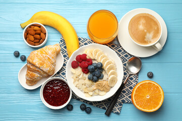 Healthy breakfast. Oatmeal with nuts, banana, berries, jam, coffee and juice served on light blue wooden table, flat lay