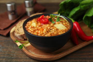 Delicious lentil soup with vegetables served on wooden table, closeup