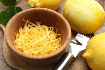 Lemon zest, fresh fruits and zester tool on wooden table, closeup