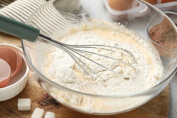 Different ingredients for dough and whisk on table, closeup