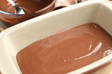 Liquid chocolate dough in baking dish on table, closeup