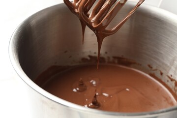 Chocolate dough dripping from mixer into bowl, closeup