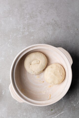 overhead view of shaped raw scallion pancakes in a donabe, top view of shaped scallion pancake dough