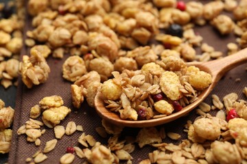 Tasty granola with dried fruits and spoon on table, closeup