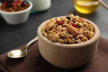 Tasty granola with dried fruits, nuts and honey on black table, closeup. Space for text