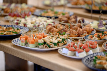 Buffet with mini appetizers, croissants, canapes and tartlets on a wooden table.