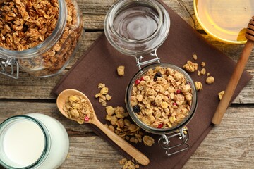 Tasty granola with dried fruits, milk and honey on wooden table, flat lay