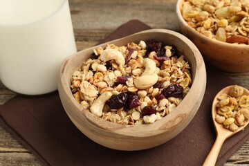 Tasty granola with dried fruits, nuts and milk on wooden table, closeup