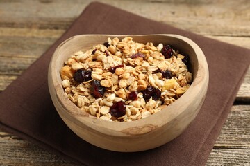 Tasty granola with dried fruits in bowl on wooden table, closeup