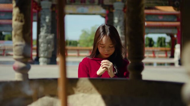 At a lively Chinese temple, young asian woman to pray and present offerings, seeking blessings for their families as they celebrate the joyous occasion of the Chinese New Year.