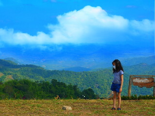 Fototapeta premium The girl stands in the middle of the valley landscape.