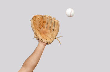 Man's hand with leather baseball glove reaches out to catch ball in air, dynamic sports action.