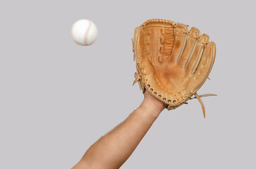 Man's hand with leather baseball glove reaches out to catch ball in air, dynamic sports action.