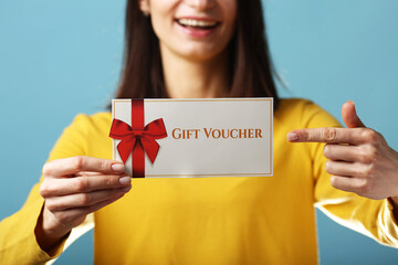 Joyful young brunette woman girl in yellow sweater posing isolated on pastel ,blue background studio portrait. People lifestyle concept. Mock up copy space. Hold gift certificate, doing winner gesture